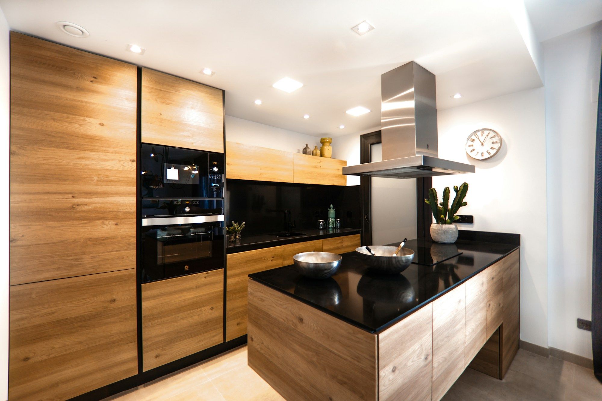 Cocina con isla de madera, encimera negra y columnas de madera